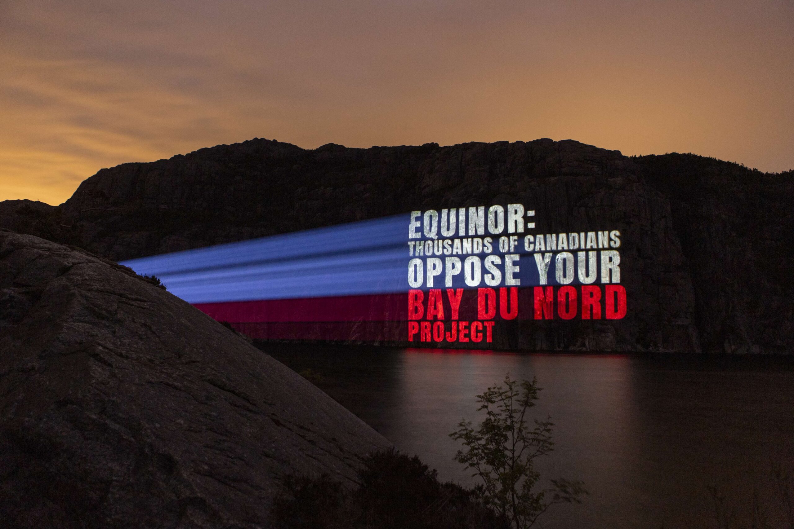 Photo of light projection on Lysefjord in Norway reading Equinor Thousands of Canadians oppose your bay du nord project