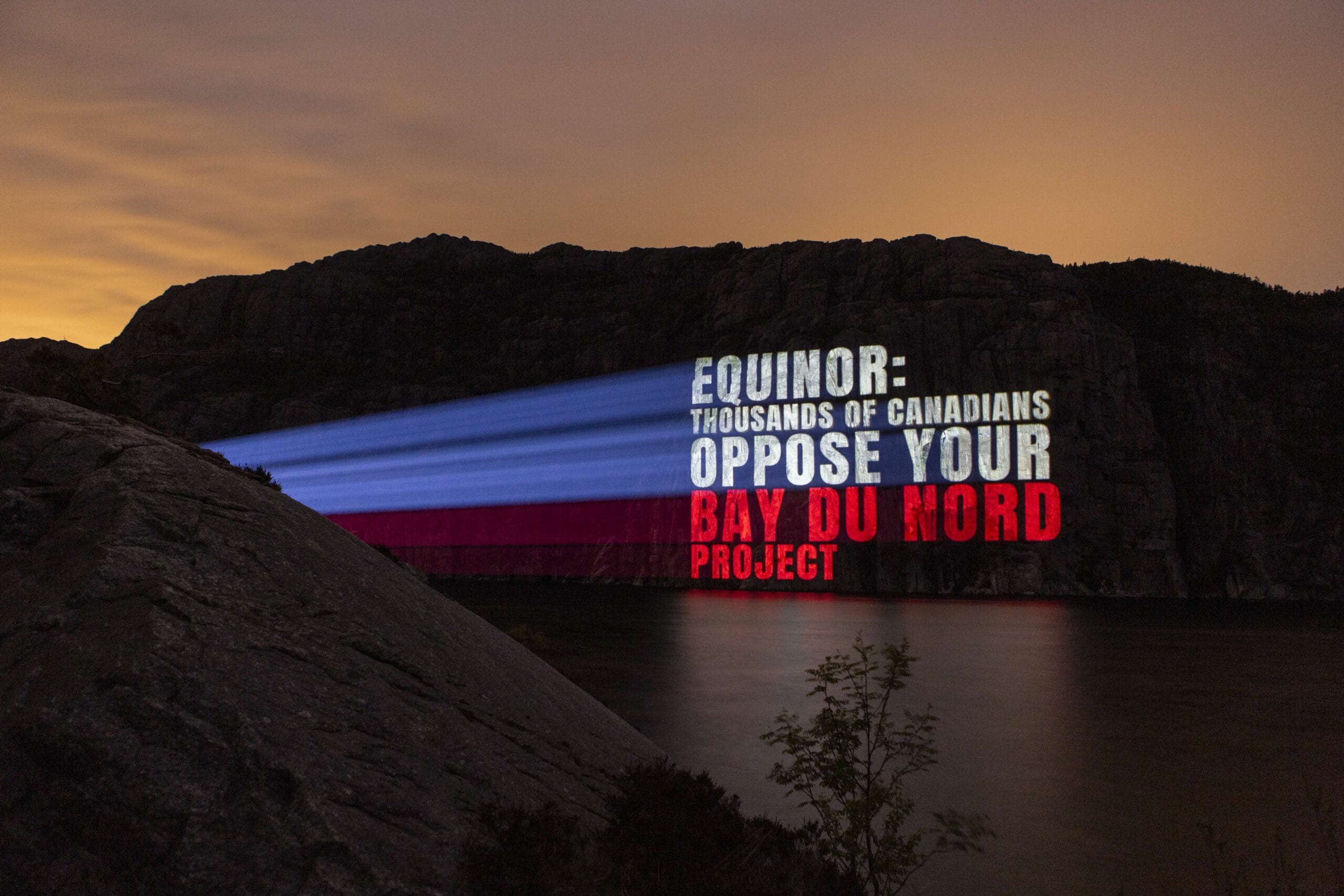 Photo of light projection on Lysefjord in Norway reading Equinor Thousands of Canadians oppose your bay du nord project