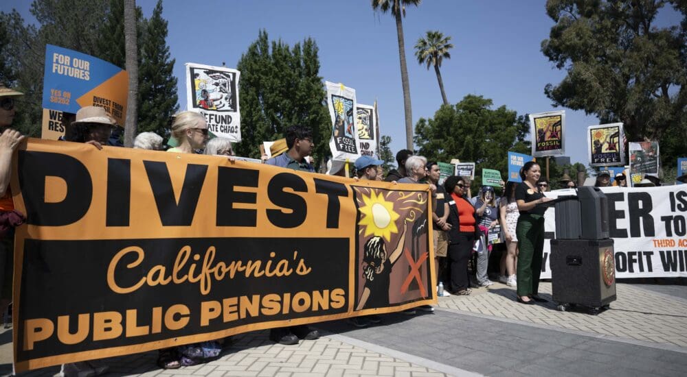 Group of Californians at a press conference behind an orange banner reading "Divest California's Public Pensions"