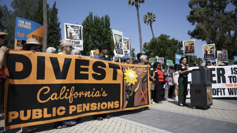 Group of Californians at a press conference behind an orange banner reading "Divest California's Public Pensions"