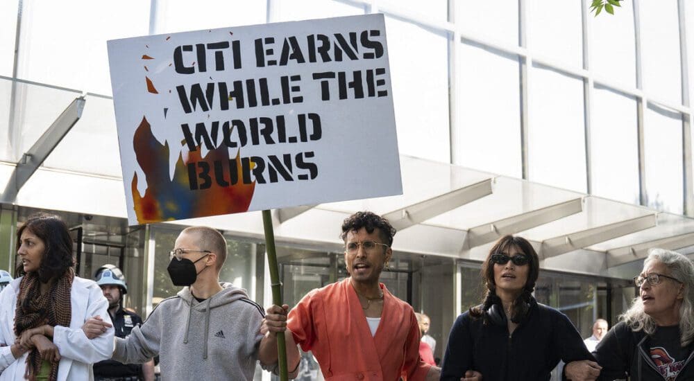 5 people outside Citibank NYC HQ with a poster reading "Citi earns while the world burns"