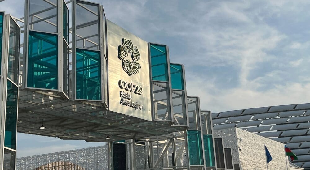 COP29 Conference entrance building with a big sign that reads "COP29, Baku, Azerbaijan" in silver text