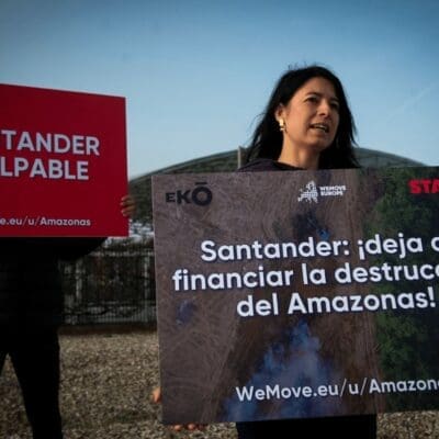 Two people holding posters outside the Santander AGM.