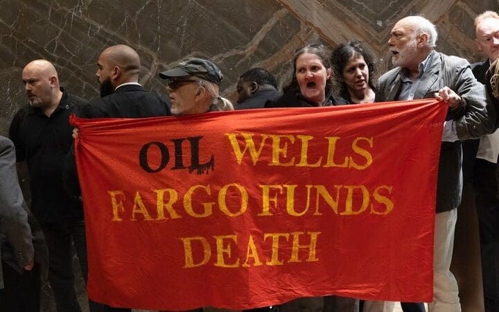 Group of people holding a red banner reading "oil wells fargo funds death"